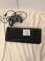 Razer keyboard and Logitech wired controller on cream surface