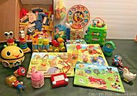 Photo showing assortment of baby toys including wooden puzzles, blocks, learning cubes, stacking blocks, and various figures and electronic toys arranged on dark surface.