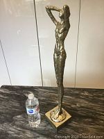 Side angle photo of bronze statue showing surface texture and profile.