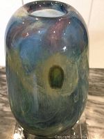 Front angled view of the mouthblown vase showing multicolored swirled hues in blue, yellow, green, and pink tones.