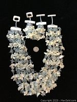 Full view of necklace and bracelet laid side by side on black background with quarter for size reference.