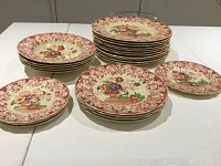 Photo showing stacks of large dinner plates, salad/soup bowls, dessert plates, bread plates and an appetizer plate all with Pomeroy red multicolor floral pattern.
