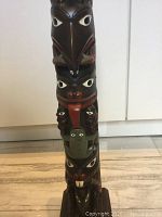 Front view of vintage wooden totem pole figurine showing carved animal faces with painted details