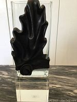 Front view of the vase with the black leather moulded leaf cover fitted on the glass vase, displayed against a neutral background.