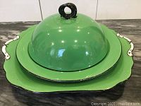 Front view of the stacked tray, plate, and muffin dome showing green finish and black trim.