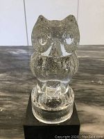 Front view of the vintage glass Goebel owl figurine showing the owl perched on the round base, placed on black platform, detailed owl eyes and body visible.