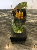 Clear lead crystal paperweight showing detailed yellow Anemone flower with green leaves on black base.