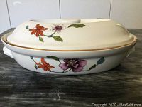 Side view of covered casserole dish showing floral pattern and gold rim.