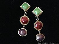 Pair of mid-century clip-on drop earrings with green, red, and purple enamel drops on a black background.