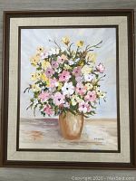Full view of framed floral painting showing bouquet of pink, yellow, and white flowers in beige vase on neutral surface.