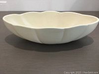 Side view of white oblong scalloped ceramic bowl showing curved edges and smooth glaze.