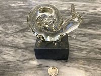 Front view of clear Murano glass snail figurine on black marble base with quarter coin for scale