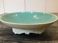 Side view of the mid-century ceramic bowl showing turquoise interior and ornate white base.