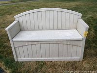 Front view of white plastic patio storage bench with curved backrest and armrests, closed lid.