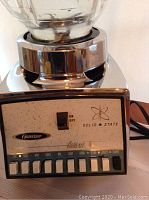 Close-up of the Osterizer vintage blender control panel with labeled function buttons and solid state branding.