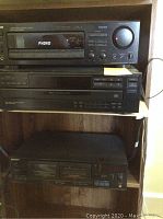 Sony stereo system stacked on dark wood shelf including STR-D565 receiver (top), CDP-C265 CD player (middle), and TC-WR465 cassette deck (bottom).