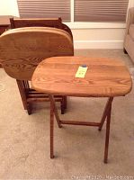 Photo of four solid wood tray tables, one open and others positioned in the wooden carrier, showing wood grain and folding legs.