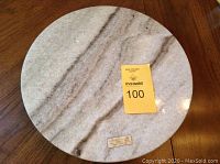 Top-down photo of the 14 inch round marble turntable with natural streaks, showing seller's auction tag.