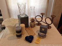 Full lot tabletop view including glass vases, brass horn candle holders, Hobnail milk glass vase, candles, paperweight, and Wedgwood box.