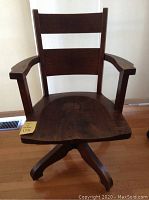 Frontal view showing ladder back with two horizontal slats, contoured wooden seat, armrests, five-leg base on casters