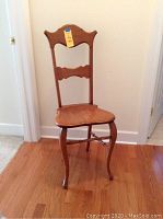 Full view of the handmade solid oak chair showing the contoured seat, carved backrest and curved legs.