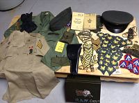 Overview of lot showing uniforms, patches, military cap, gloves, guide books, and other accessories arranged on table.
