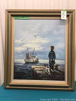 Front view of framed painting showing boy, dog, boat scene