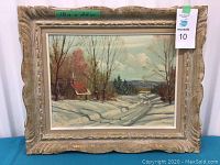 Full front view of framed winter landscape painting with green tape showing dimensions and auction tag