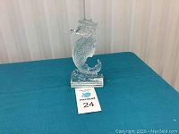 Front view of clear Waterford Crystal seahorse figurine placed on a blue cloth surface with a MaxSold auction lot number card visible in front.