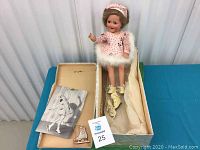 Doll seated in original box with paper flyer and lot tag visible