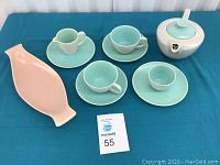 Full tea set and pink platter displayed on blue cloth