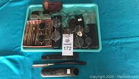 Lot showing multiple wire-framed antique spectacles, loose lenses in cardboard holders, black spectacle cases, and a straight razor with two sheaths laid on a turquoise surface.