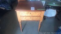 Front view of wooden end table showing two drawers and turned legs