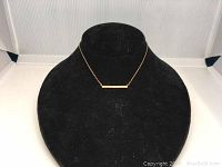 Frontal view of delicate Swarovski VI rose gold necklace displayed on black jewelry bust, showing horizontal bar pendant with crystals.