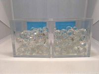 Two clear acrylic display cases filled with multiple small clear crystal balls showing iridescent prism effects under light.