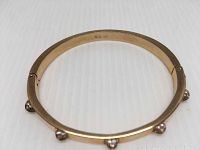 Clear image of rose gold-tone bangle with crystal accents on a white surface, showing circular shape and crystal placement.