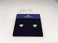 Pair of Swarovski heart-shaped pierced earrings displayed on original Swarovski card with clear crystals covering the hearts.