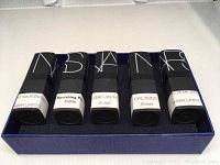 Five NARS lipsticks arranged inside blue box, showing labels with shade names Start Your Engines Sheer, Ravishing Rose Matte, Bulgarian Rose Sheer, Cruising Sheer, Belle de Jour Sheer.