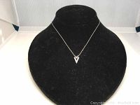 Front view of Swarovski small V-shaped crystal pendant necklace on display bust with black velvet background.