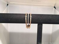 Front view of the Swarovski gold-tone bracelet with crystals displayed on black stand.