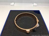 Rose gold tone Swarovski bracelet viewed from the side, showing band and hinge mechanism.