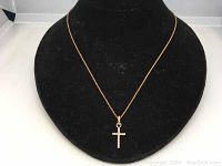 Gold plated Swarovski cross necklace displayed on a black necklace stand showing details of the cross pendant and chain.