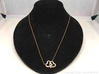 Gold plated double heart necklace displayed on black mannequin bust, showing detail of two hearts, one with crystals.
