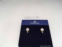 Front view of Swarovski crystal faux pearl earrings on branded blue card.