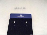 Small Swarovski crystal earrings mounted on silver displayed on a dark blue Swarovski card holder on white background.
