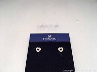 Photo of Swarovski earrings displayed on a black card with Swarovski branding showing the heart-shaped crystal earrings.