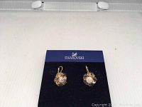 Pair of Swarovski pink flower crystal earrings on Swarovski blue card holder, shown from front