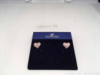 Front view of both Swarovski crystal heart stud earrings on blue branded backing card.