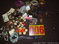 Photo showing assorted earrings and various beaded and button necklaces spread on a dark surface.