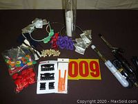 Photo showing the two curling irons, hair ribbons, clips, elastic bands, decorative flowers and other hair accessories laid out on a table with a lot number.